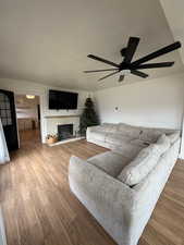 Living area with a fireplace, wood finished floors, a ceiling fan, and a textured ceiling