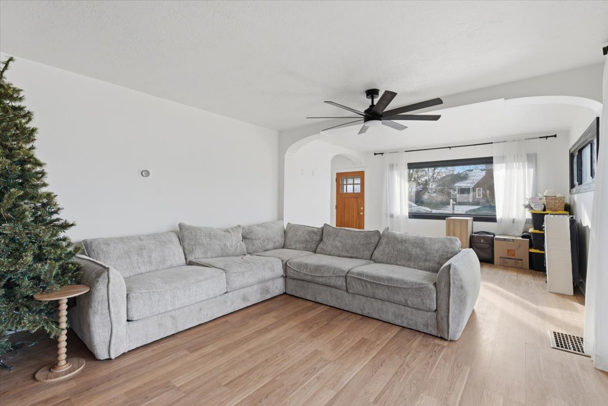 Living room featuring arched walkways, light wood-style floors, and a ceiling fan