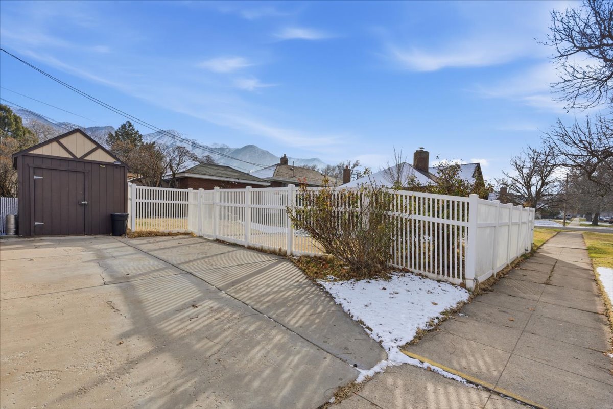 Exterior space with a fenced front yard, a mountain view, a shed, and a gate