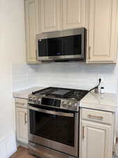 Kitchen featuring light countertops, appliances with stainless steel finishes, wood finished floors, and tasteful backsplash