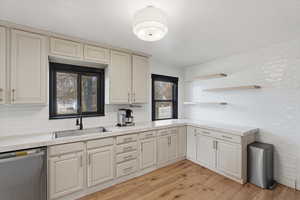 Kitchen featuring dishwasher, light countertops, open shelves, light wood finished floors, and tasteful backsplash
