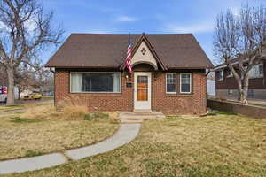 View of front of property featuring a front lawn, brick siding, and roof with shingles