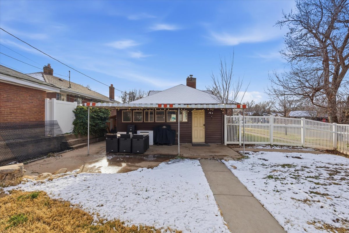 Snow covered property with a patio area and a chimney