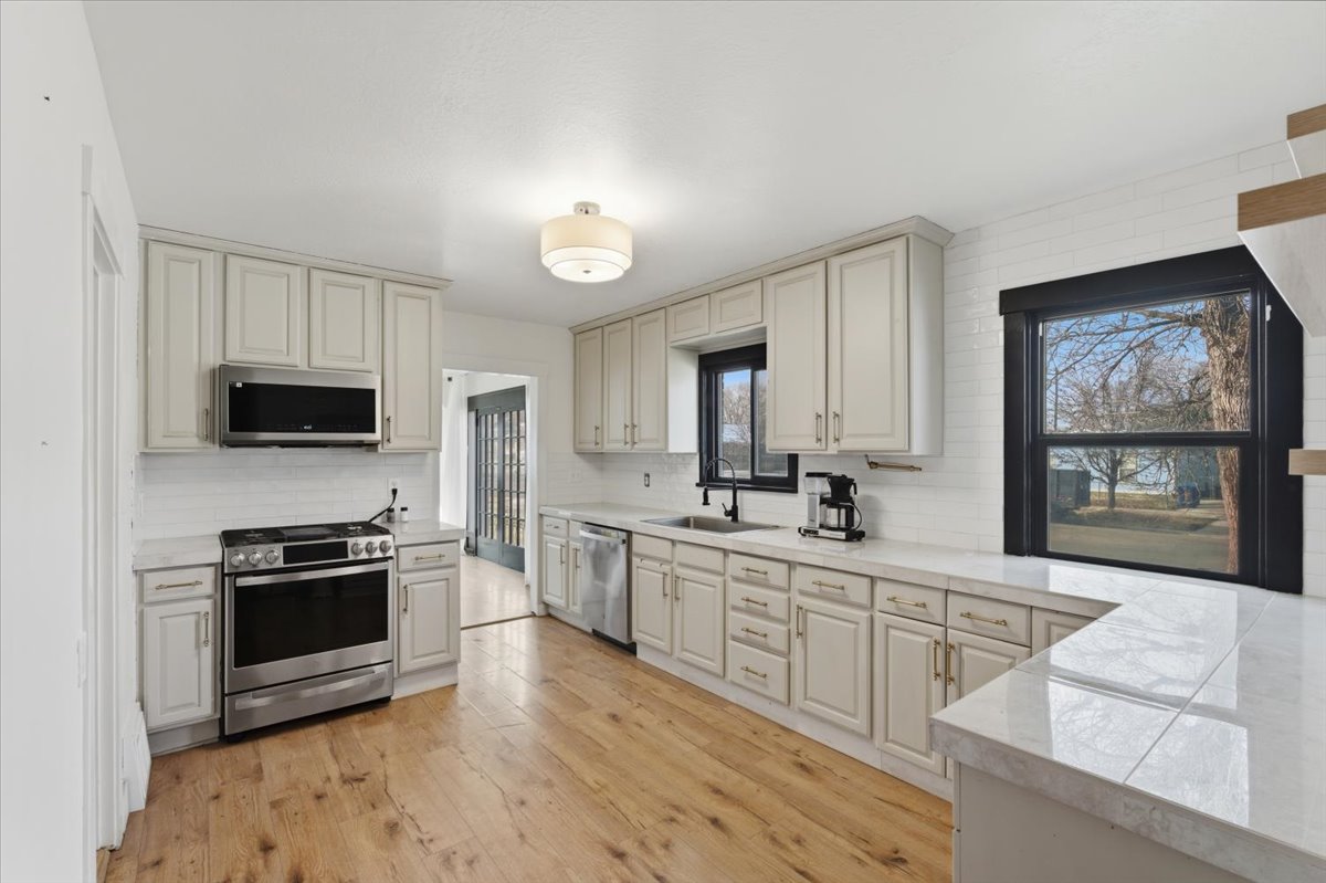 Kitchen featuring stainless steel appliances, light countertops, light wood-type flooring, and backsplash
