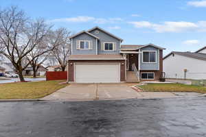 Split level home featuring driveway, a garage, brick, siding, and roof with shingles