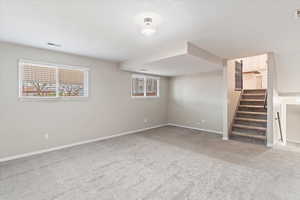 Basement with light carpet and stairs