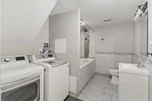 Laundry area featuring washer and clothes dryer, tile walls, and a textured ceiling