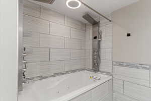 Full bath featuring a combined bath / shower with double head rainfall shower and tile walls