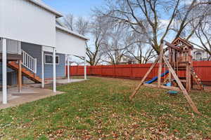 Fenced backyard with a patio area, stairway, and a playground