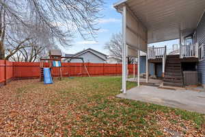 Fenced backyard with a patio area, stairs, a playground, and a wooden deck