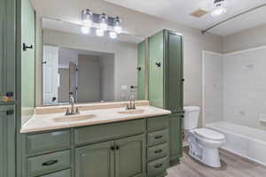 Bathroom featuring double vanity, light wood-type flooring, and shower / washtub combination