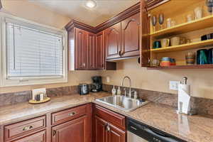 Kitchen with open shelves, dishwasher, light stone counters, and a textured ceiling