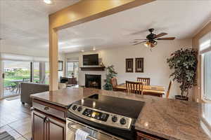 Kitchen with stainless steel range with electric stovetop, dark stone countertops, plenty of natural light, a fireplace, and a textured ceiling