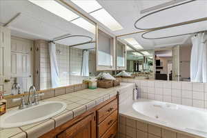 Full bath featuring a tub with jets, vanity, and a tile shower
