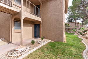 Entrance to property with stucco siding and a lawn