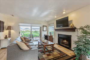 Living area with a lit fireplace, a textured ceiling, and light wood-style floors