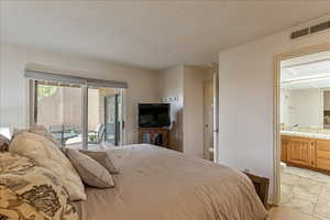 Bedroom featuring access to outside, a textured ceiling, ensuite bathroom, and light wood finished floors