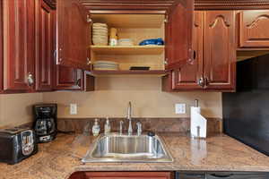 Kitchen featuring light stone countertops and open shelves