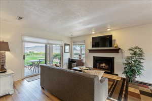 Living room featuring wood-type flooring, a lit fireplace, and a textured ceiling