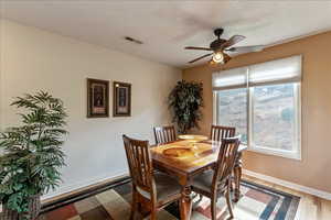Dining room with light wood finished floors, a ceiling fan, and a textured ceiling