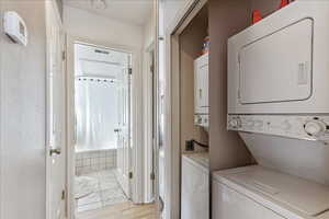 Laundry area featuring stacked washer and clothes dryer and light wood-type flooring