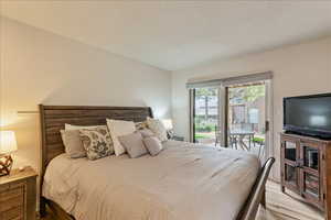 Bedroom featuring access to exterior, a textured ceiling, and wood finished floors