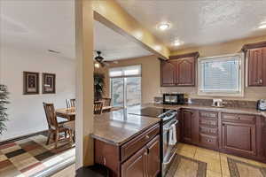 Kitchen featuring electric stove, light tile patterned floors, a peninsula, black microwave, and a textured ceiling