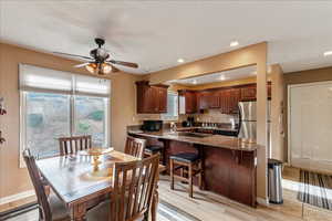 Dining space with a ceiling fan and light wood-type flooring