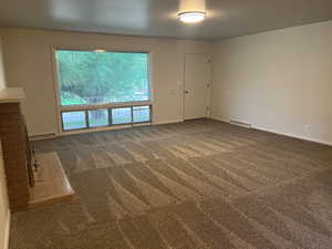 Unfurnished living room with dark colored carpet and baseboards
