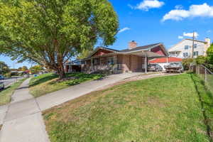 View of front of home with an attached carport, a chimney, covered porch, brick siding, and driveway
