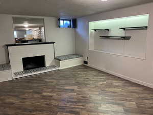 Unfurnished living room featuring dark wood-style flooring, a fireplace, and a textured ceiling