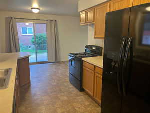 Kitchen featuring black appliances, light countertops, and brown cabinetry