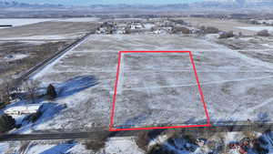 Snowy aerial view featuring property parcel outlined and a mountain view