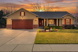 View of front facade featuring brick siding, covered porch, a front yard, and concrete driveway