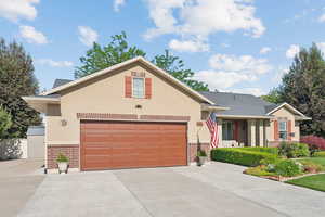 View of front of house with brick siding, driveway, a garage, and stucco siding