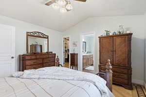 Bedroom with a walk in closet, lofted ceiling, a ceiling fan, and light wood finished floors