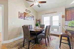 Dining area with vaulted ceiling, ceiling fan, and light wood-style floors