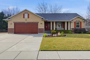 View of front facade featuring brick siding, a front lawn, concrete driveway, and stucco siding