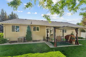 Rear view of property with a lawn, roof with shingles, and a patio