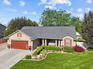 View of front of home featuring brick siding, covered porch, driveway, a garage, and stucco siding