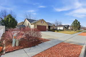 Single story home with concrete driveway, an attached garage, stucco siding, a residential view, and brick siding