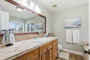 Bathroom with vanity, a chandelier, and tiled bath