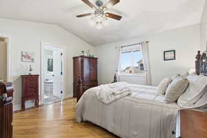Bedroom featuring light wood-style floors, lofted ceiling, ceiling fan, and ensuite bathroom