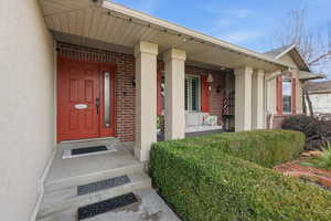 Entrance to property with a porch and brick siding
