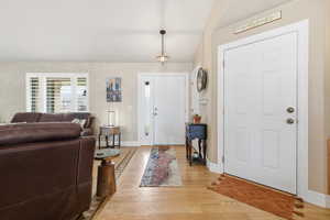 Entrance foyer with wood finished floors and lofted ceiling