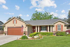 View of front of property with brick siding, a front lawn, concrete driveway, and covered porch