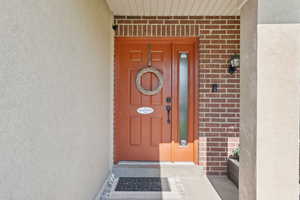 Doorway to property featuring brick siding and stucco siding
