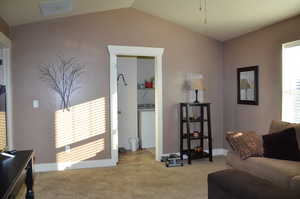 Living room with vaulted ceiling, washer / dryer, and carpet