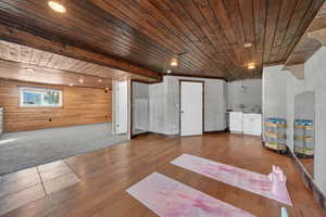 Basement with wood ceiling, wooden walls, hardwood / wood-style flooring, recessed lighting, and carpet floors
