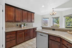 Kitchen with dishwasher, decorative backsplash, vaulted ceiling, light granitecountertops, and decorative light fixtures